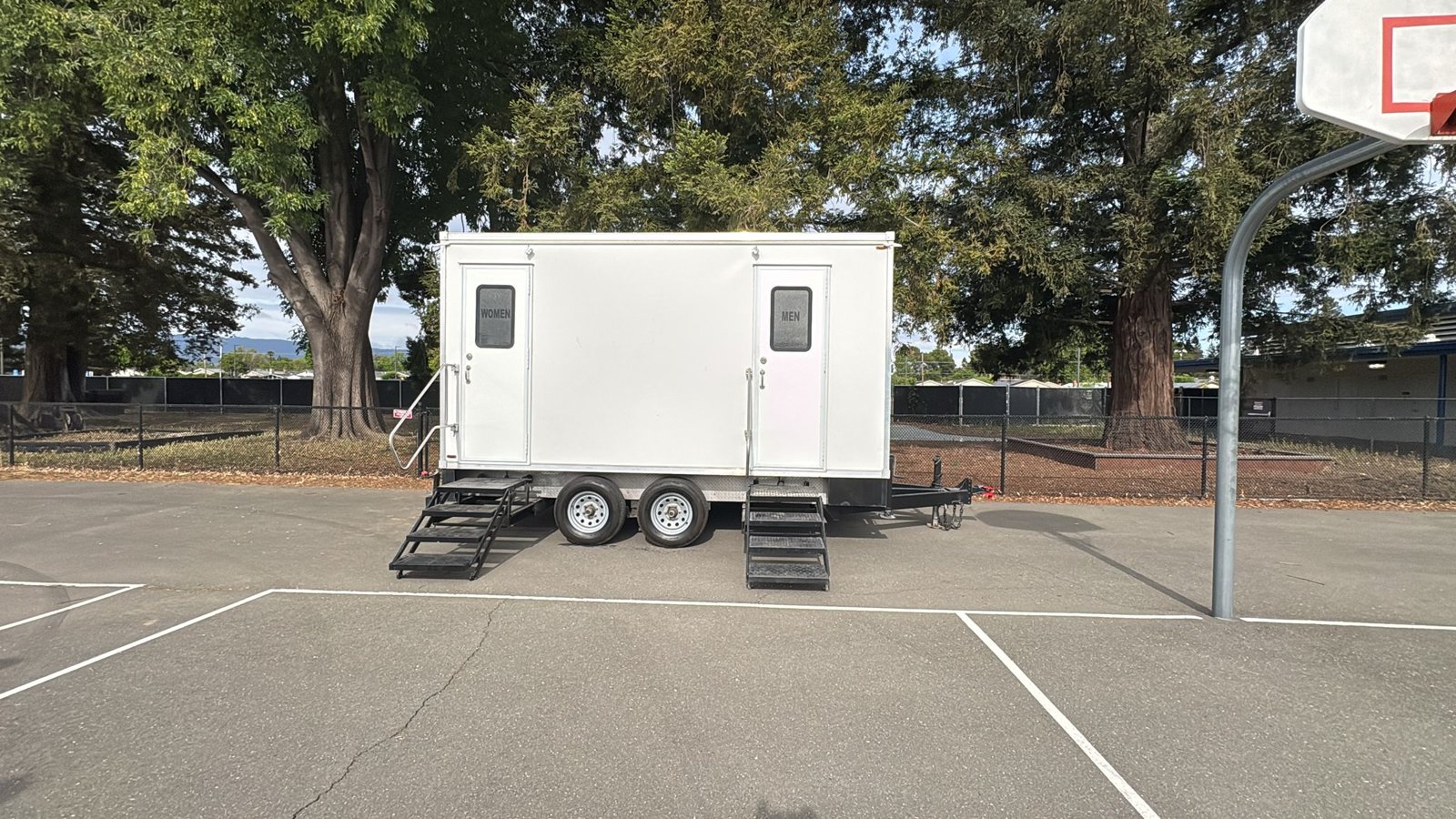 2-stall portable bathroom trailer with women's and men's doors set on a school blacktop in the Santa Clara area, The Lavatory NorCal